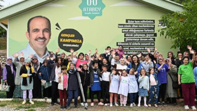 Etkinliğe katılan engelli bireyler ve aileleri birlikte fotoğrafta el sallıyorlar.