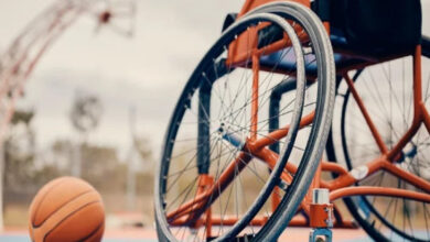 Basketbol sahasında boş bir tekerlekli sandalye ve yanında bir basketbol topu var.