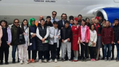 Türk Hava Yolları Ağrı Ofisi yetkilileri ve engelli bireyler uçak önünde fotoğraf çektiriyor.