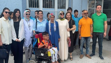 Akülü tekerlekli sandalye kullanıcısı Yasin Arda Boz, okul bahçesinde ailesi, öğretmenleri ve arkadaşlarıyla fotoğraf çekiliyor.