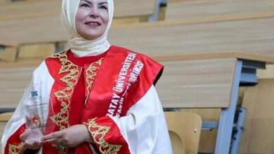 Gülistan Ekin Sarkurt, mezuniyet töreninde giydiği avukat cüppesi ile üniversitede anfi sınıfında ayakta duruyor.