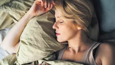 Sarışın bir kadın, yatakta uyurken fotoğrafa bakılan açıya göre sol tarafa dönerek kolunu yastığın altına katmış.