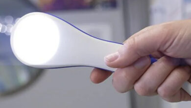 Görselde uzay saç kurutma makinesi olarak adlandırılan cihaz var ve cihazı beyaz renkli ucundan bir kişi tutuyor, cihazdan ise beyaz yoğun bir ışık kaynağı ortaya çıkıyor.