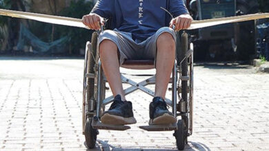 Tekerlekli sandalye kullanan engelli bireyin boyundan aşağısı ve tekerlekli sandalyenin her iki tarafındaki kol katma alanına iki tane kanat şeklinde karton takılı.