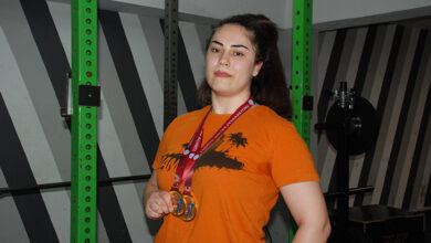 Görme engelli Melisa Durak, boynunda asılı olan madalyalarını tutarak fotoğraf için poz veriyor.