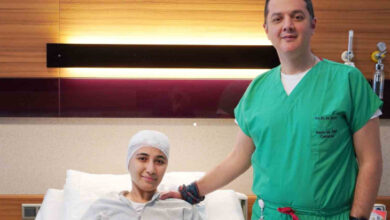 Parkinson hastası Demet Kaya, ameliyat sonrası kafası sargılı hasta yatağındayken doktoru Doç. Dr. Ali Akay ile fotoğraf çekiliyor.