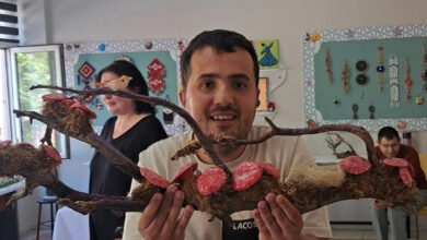 Erkek engelli bir öğrenci atık malzemelerden yaptığı bir eseri elinde kameraya doğru tutuyor.