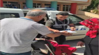 Polis memuru, tekerlekli sandalyedeki engelli öğrenciyi sınav giriş kağıdını kontrol ediyor.