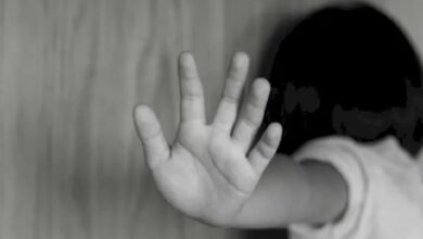 Sırtı dönük çocuk, kafasını duvara yaslayarak, elini "dur"dercesine omuz hizasına kaldırmış.