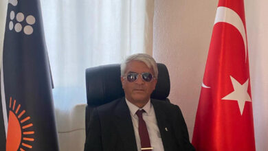 Türkiye Görme Engellileri Muğla Şube Başkanı Mehmet Özdemir, dernek odasında oturuyor ve fotoğrafa göre sağda Türk bayrağı, solda ise dernek bayrağı var.