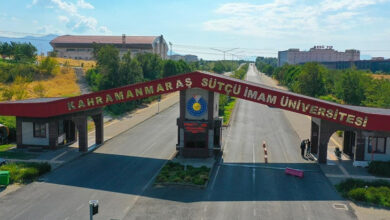 Fotoğrafta, üniversitenin girişinde altın sarısı renklerle bordo duvar üzerine "Kahramanmaraş Sütçü İmam Üniversitesi" yazıyor.