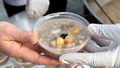 Plastik kap içinde aşure dağıtımı yapılıyor.