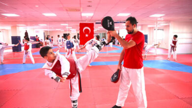 Engelli sporcu Süleyman Metin, tekvando antremanında bacaklarını yukarı doğru açarak, antrenörün elindeki tekmeliğe vuruyor.