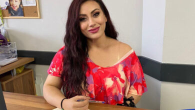 EÇSAV Sözcüsü Ezgi Kılıç, bir elini masaya katmış ve elinde ise bir tükenmez kalem tutarak fotoğraf için poz vermiş.