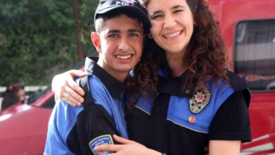 Engelli Furkan Susam, polis üniforması giymiş ve bir polis memuru ile sarılarak gülümsüyor.