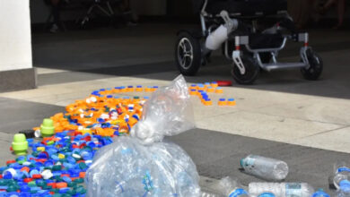 Yere serilmiş plastik şişe kapakları ve akülü tekerlekli sandalye görselde var.