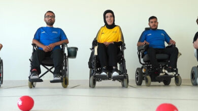 Fotoğrafta yer alan üç tekerlekli sandalye kullanıcısı sporcu var. Ortada kadın tekerlekli sandalye kullanan sporcu ve sağında, solunda erkek tekerlekli sandalye kullanan sporcular var.