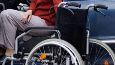 Tekerlekli sandalye kullanıcı engelli birey, otomobilin sürücü koltuğundan tekerlekli sandalyeye geçmeye çalışıyor.