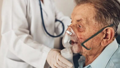 Beyaz önlüklü bir doktor, hastaya oksijen maskesi takıyor.