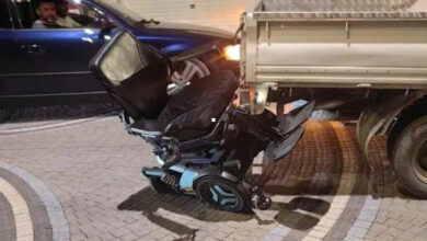 Akülü tekerlekli sandalye, kamyonetin arkasına takılarak yan yatmış.