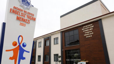 Fotoğrafta bir binanın dışında "AKSARAY BELEDİYESİ ENGELSİZ YAŞAM MERKEZİ 2023" yazısı ve binanın önünde bulunan tabelada "AKSARAY BELEDİYESİ ENGELSİZ YAŞAM MERKEZİ" yazısı, altında ise turuncu ve mavi renkli insan çizimleri ellerini yukarı doğru kaldırarak birleştirmişler.