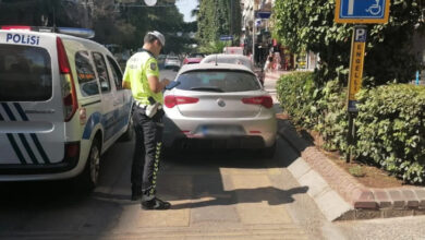 Fotoğrafta, engelli park yeri tabelası olan alana, engelli olmayan bir sürücünün park etmesinden dolayı trafik polisi ceza yazıyor. Trafik polisi arabanın plakasının olduğu yerde elindeki kağıda bir şeyler yazıyor.