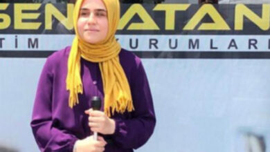 Görme engelli öğrenci Feyzanur Kaya, mezun olduğu okulun önünden fotoğraf çekiliyor. Kaya’nın elinde beyaz baston var.