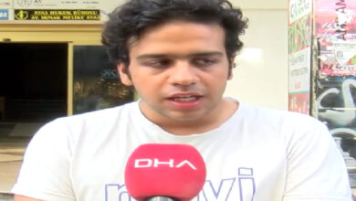 Tekerlekli sandalye kullanıcısı engelli birey Emir Ali Najjariyeh, kırmızı renkli üzerinde DHA yazan bir mikrofona doğru konuşuyor.