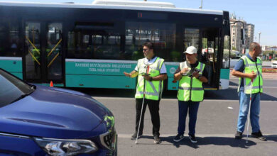 Fotoğrafta, trafik polisi üniforması giymiş üç erkek var. Ellerinde beyaz baston tutan kişiler trafik denetlemesine katılıyor.
