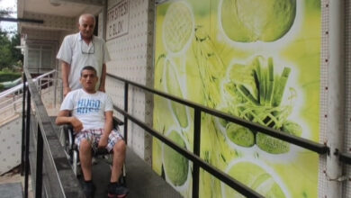 Tekerlekli sandalye kullanan engelli birey Mustafa Kıraç ve babası Süleyman Kıraç engelli rampasını kullanarak binanın önüne çıkıyorlar.