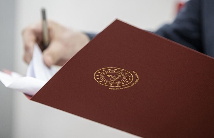 Fotoğrafta, kahverengi tonuna yakın bir dosya ve dosyanın üzerinde tutan bir çift el var.