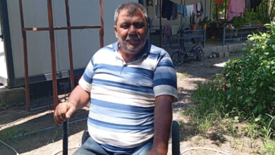 Engelli depremzede Hüseyin Köksal, plastik bir sandalye üzerinde oturuyor ve elinde bir baston var.