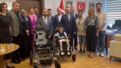 Sanayi ve Teknoloji Bakanı Mehmet Fatih Kacır ve SERÇEV yetkilileri yeni üretilen tekerlekli sandalye üzerinde serebral palsili çocukla birlikte fotoğraf karesindeler.