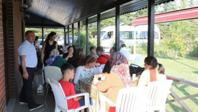 Engelli bireyler ve aileleri etkinlik için bir arada masaların etrafında oturuyor.