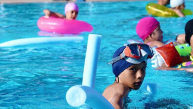 Fotoğrafta engelli çocuklar havuzda yüzüyor.