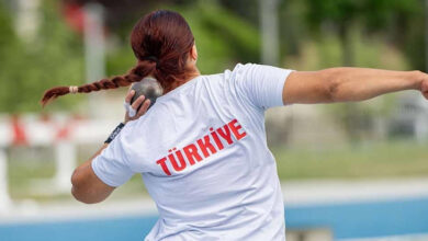Bir kadın sporcunun arka tarafından çekilmiş bir fotoğraf, sporcunun giydiği formanın sırt bölümünde "Türkiye" yazıyor ve sporcu gülle atışı yapıyor.