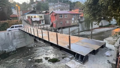 Fotoğrafta, bir dere yatağının üzerinde karşıdan karşıya geçmek için kurulmuş köprü var. Köprü çelikten yapılma ve yapımı tamamlanmamış şekilde duruyor.