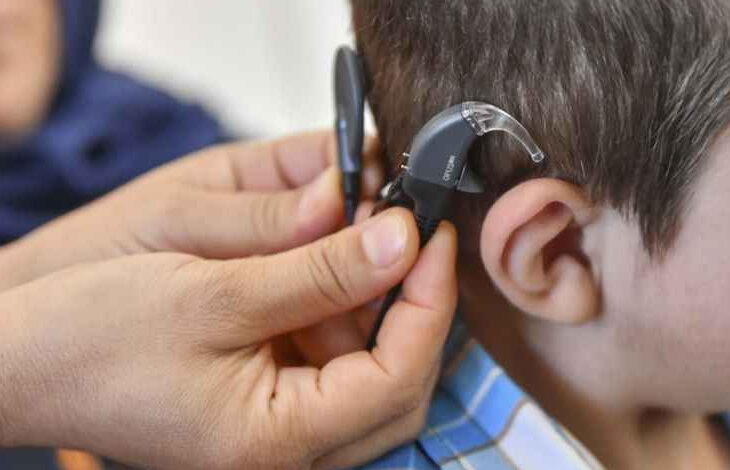 Fotoğrafta, işitme engelli bireyin kulağına işitme cihazı takılıyor.