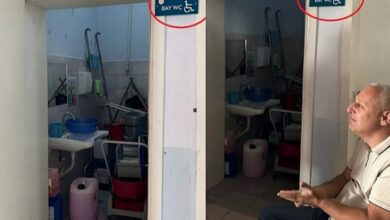 Fotoğrafta, iki fotoğraf birleştirilmiş ve tuvaletin kapısı açık şekilde çekim yapılmış. Fotoğrafın biraz dışında kalan bedensel engelli bir birey var. Tuvaletin duvarında “Bay WC” yazıyor.