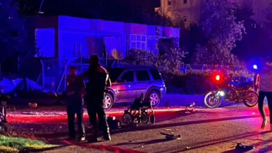 Fotoğrafta, jandarma ortada duruyor ve yanlarında parçalanmış şekilde akülü tekerlekli sandalye var. Akşam saatleri olduğu için motosikletin üzerindeki Çakar lambaları etrafı aydınlatıyor.