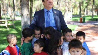 Fotoğrafta, görme engelli bireyin çevresinde birçok çocuk var.