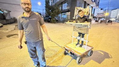 Fotoğrafta, serebral palsili çocuk kendisi için tasarlının ayakta durma sehpasında gülümseyerek ayakta duruyor. Ayakta durma sehpasının önünde çocuğun babası yaptığı özel bir kulp ile tekerleri olan sehpayı çekebiliyor.