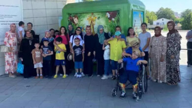 Engelli çocuklar ve aileleri birlikte toplu bir şekilde durarak fotoğraf çekiliyorlar.