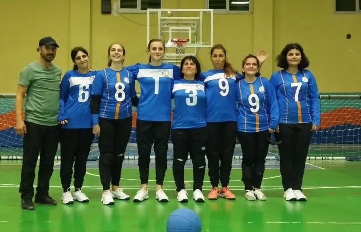 Görme Engelli Kadın Goalbol Takımı’nda yer alan sporcular fotoğrafta yan yana bir spor salonunda duruyor.