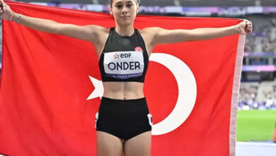 Paralimpik atletizm sporcusu Aysel Önder, her iki kolunu, iki yana doğru açarak Türk bayrağını sırt tarafında havaya doğru kaldırılmış şekilde tutuyor.