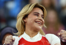 Milli para halterci Nazmiye Muratlı, her iki elini yumruk şeklini yaparak ve kafası fotoğrafa göre hafif sağa doğru dönük şekilde gülümseyerek başarısına seviniyor.