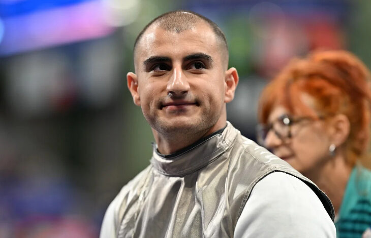 Tekerlekli sandalye eskrimde milli sporcu Hakan Akkaya, başı fotoğrafa göre sağa doğru dönük olarak bir yere doğru bakıyor ve yüzünde hafif bir tebessüm var.