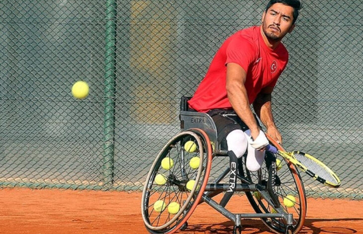 Tekerlekli sandalye tenis quad kategorisinde milli sporcu Ahmet Kaplan, elindeki tenis raketi ile topa vuruş yaptıktan sonra çekilmiş bir fotoğraf.