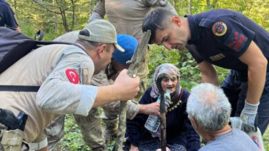 İşitme engelli birey Fikriye Özdemir, ağaçlık bir alanda yerde oturuyor. Engelli bireyin çevresinde askerler ve arama kurtarma ekipleri var.
