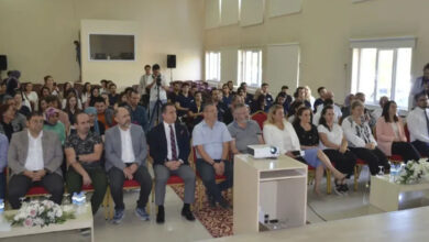 Fotoğrafta, bir konferans salonunda oturan kalabalık bir katılımcı grubuyla düzenlenen proje tanıtımı yapılıyor.